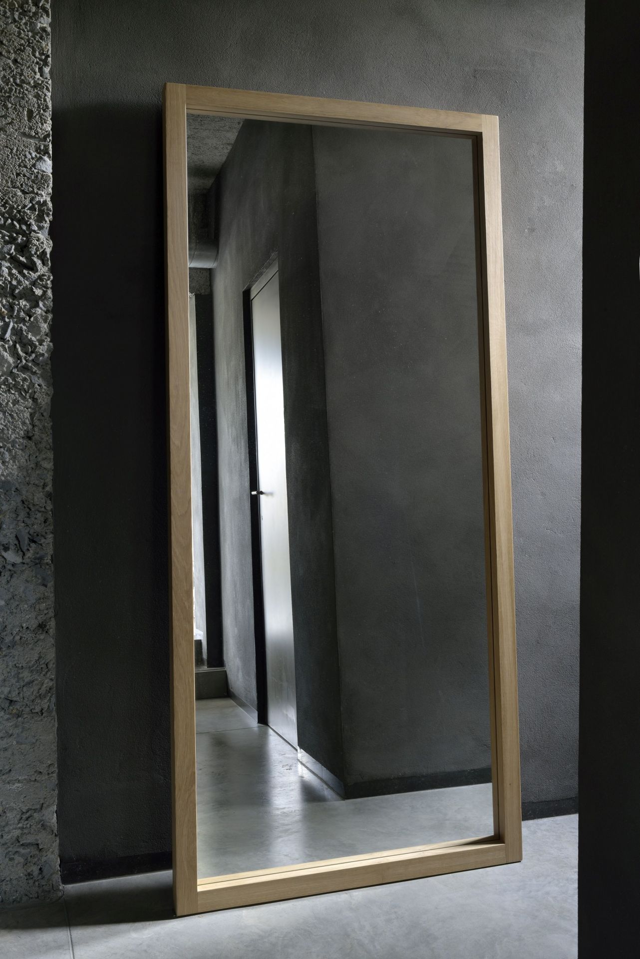 Light Frame Spiegel von Ethnicraft: Rechteckiger Spiegel mit hellem Eichenholzrahmen, stehend an grauer Wand.