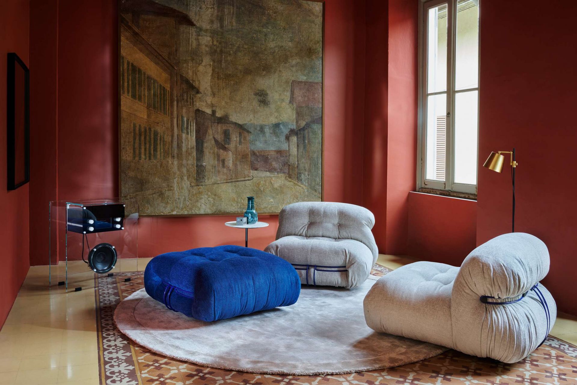 Wohnzimmer mit Cassina Soriana Sessel und Hocker in Blau und Grau auf rundem Teppich.