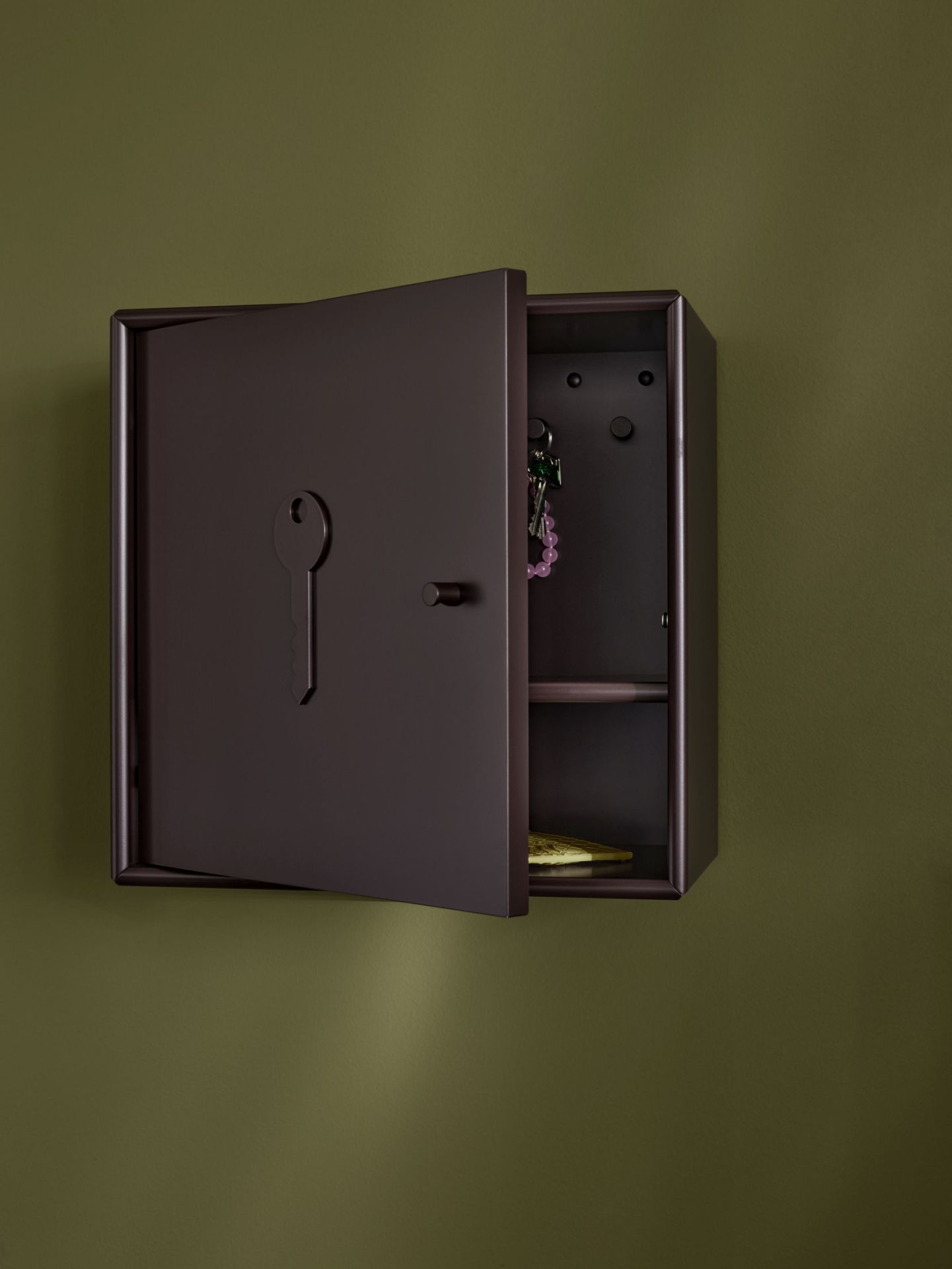 Unlock Schlüsselschrank Fennel Montana, braun, mit offener Tür an einer grünen Wand.