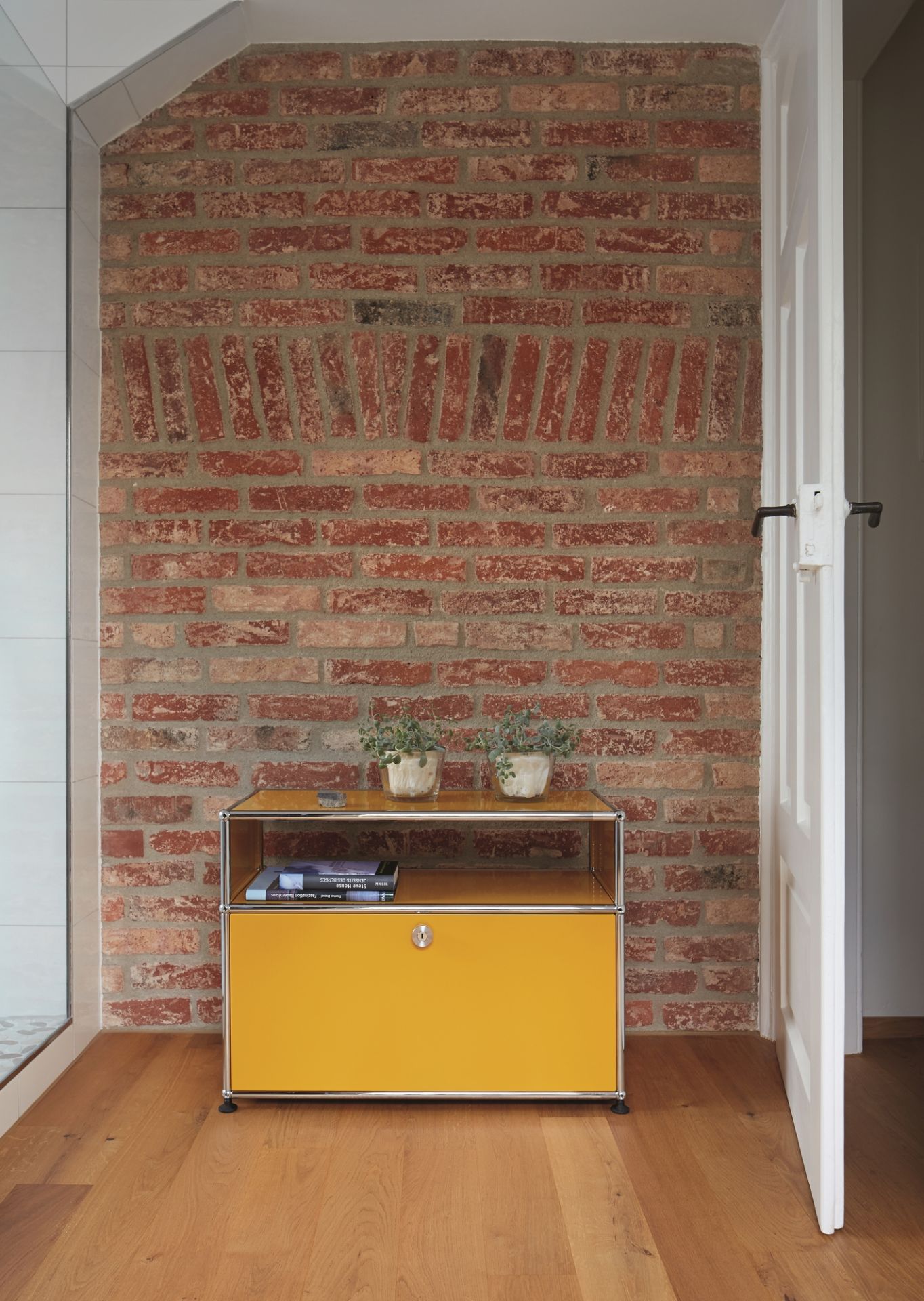 Gelbes USM Haller Beistellmöbel mit Schublade vor einer Backsteinwand und Holzboden, modernes Design.