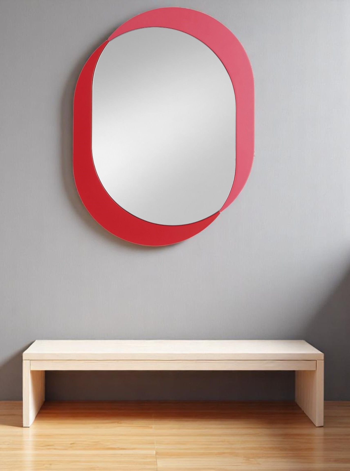 Kimo Wandspiegel von Schönbuch, oval mit rotem Rahmen, an grauer Wand über Holzbank.