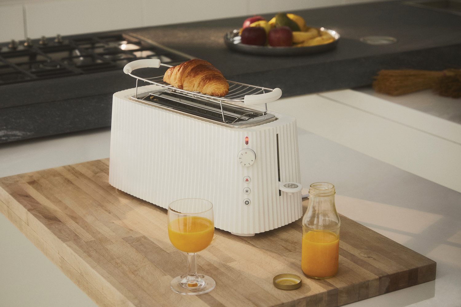 Weißer Alessi Plissé Toaster mit Croissant, Saft und Obst. Küchengerät für stilvolles Toasten.