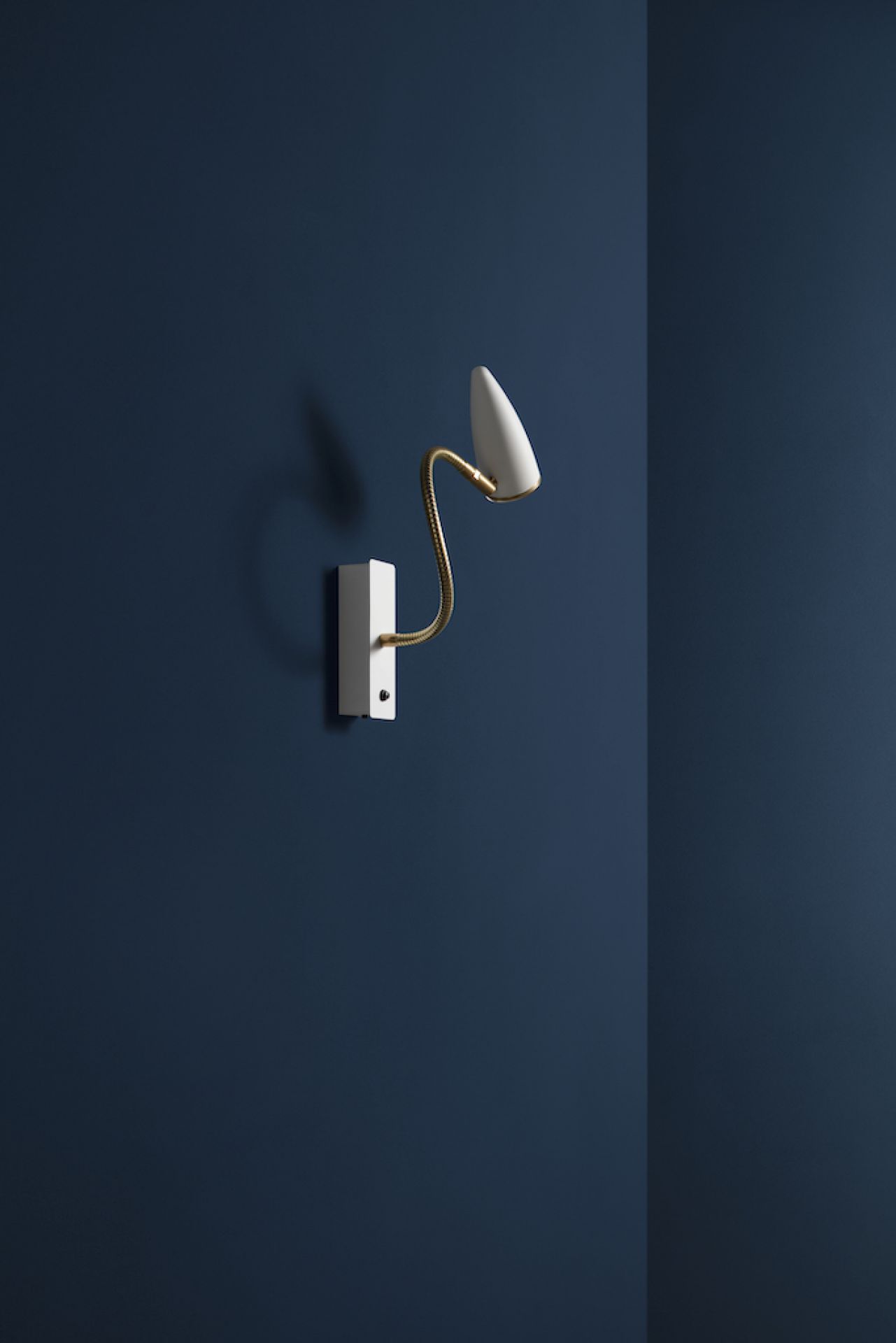 Weiße CicloItalia Wandleuchte mit flexiblem Arm und goldenen Details vor blauem Hintergrund.