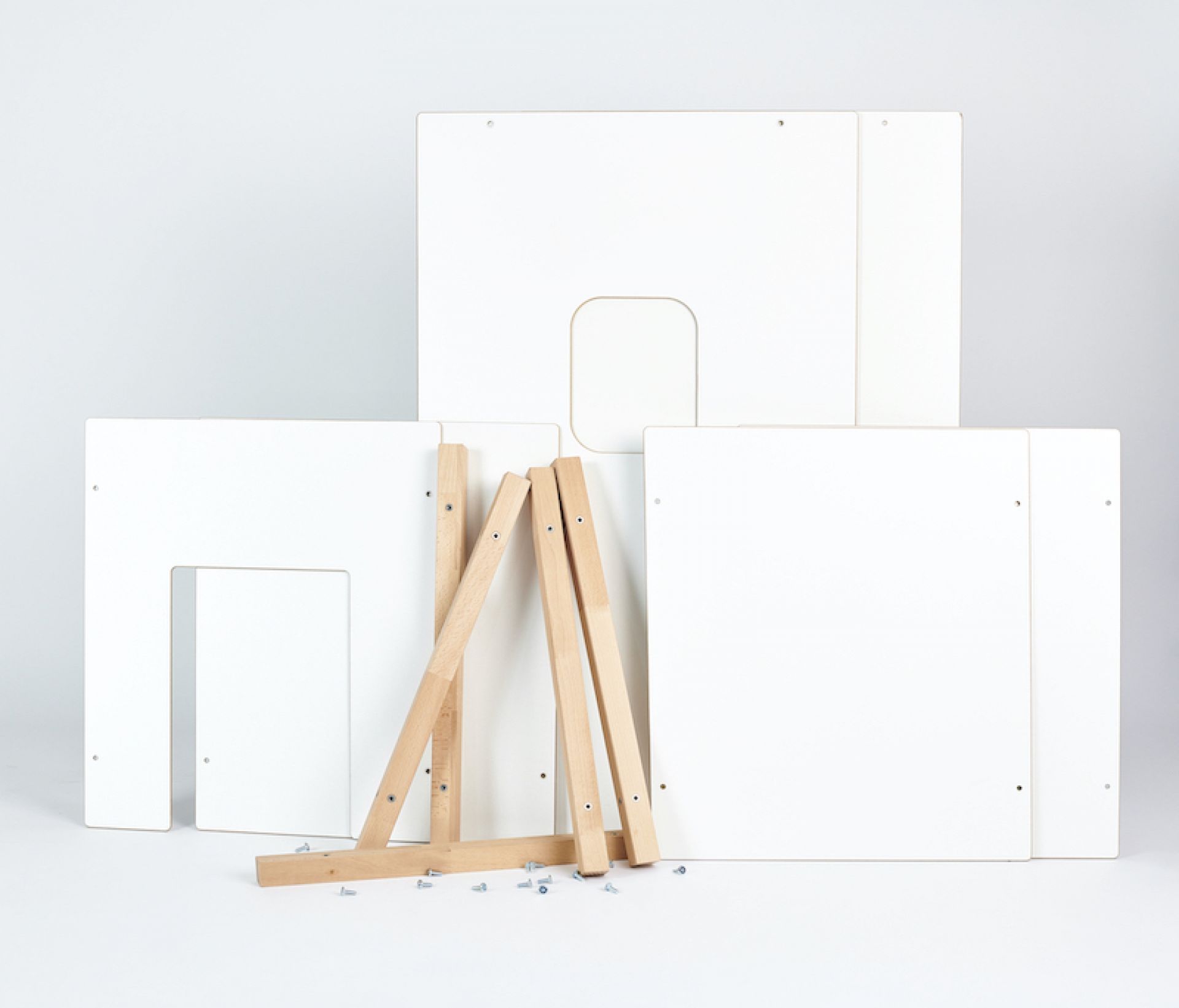Tojo Kids Wandelemente: Einzelteile der weißen Spielwand mit Holzfüßen und Schrauben im Detail.