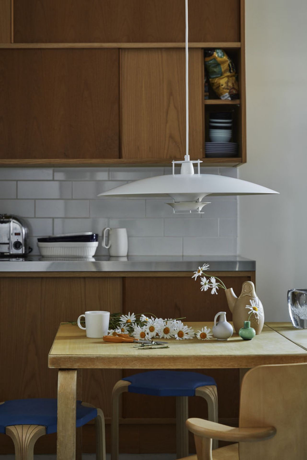 JL341 Pendelleuchte von Artek, weiße Hängelampe über Esstisch in Küche mit Blumen.