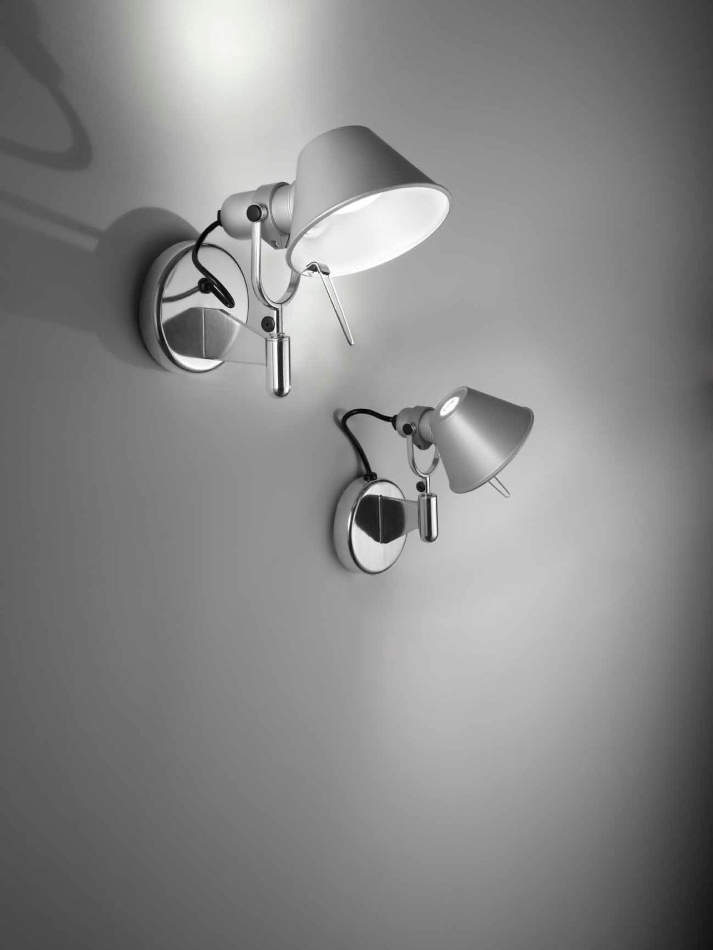 Zwei Artemide Tolomeo Micro Faretto Wandleuchten aus Aluminium in verschiedenen Positionen an einer grauen Wand.