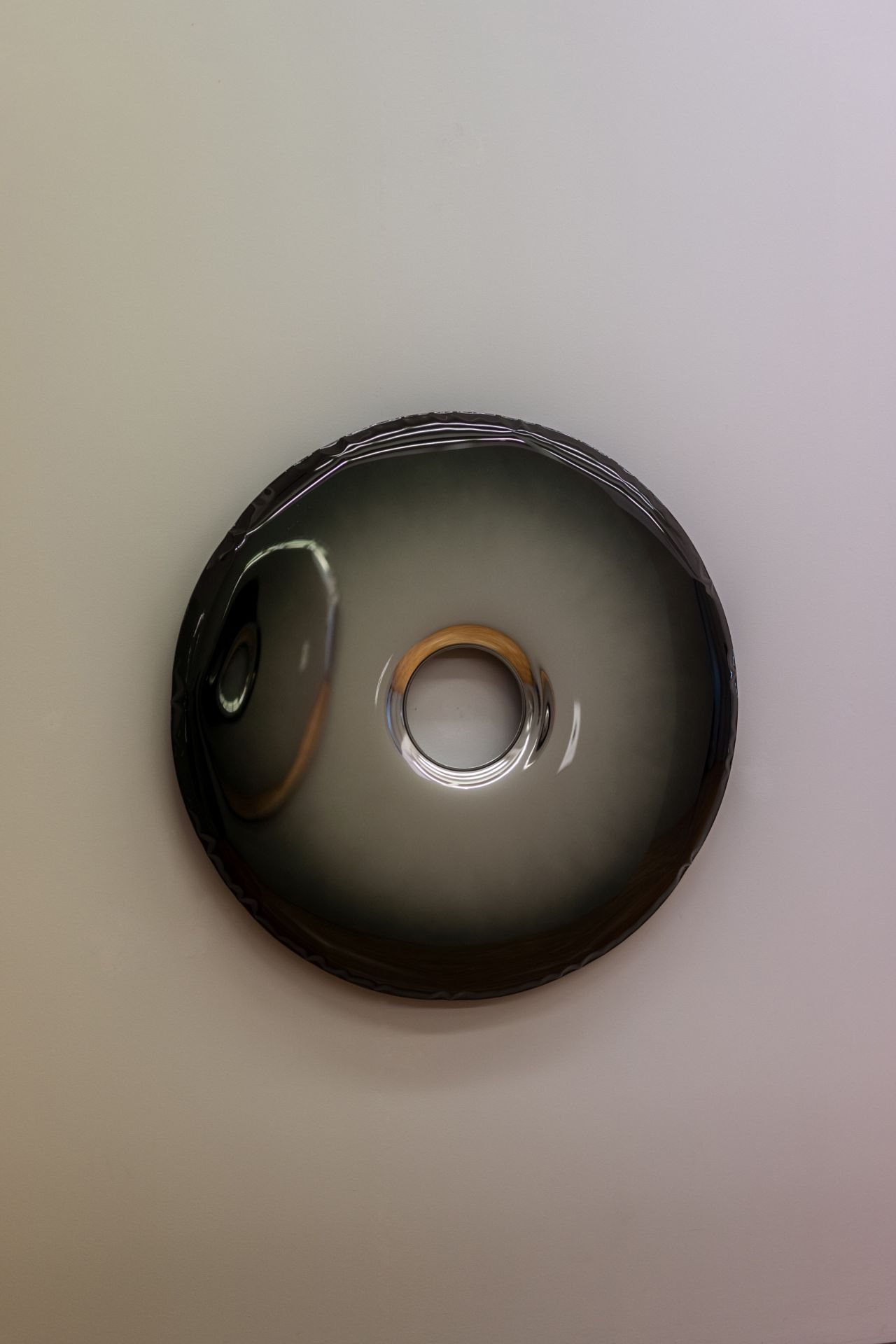 Rondo Zieta Wandobjekt in dunklem Grau mit kreisförmiger Öffnung und reflektierender Oberfläche.