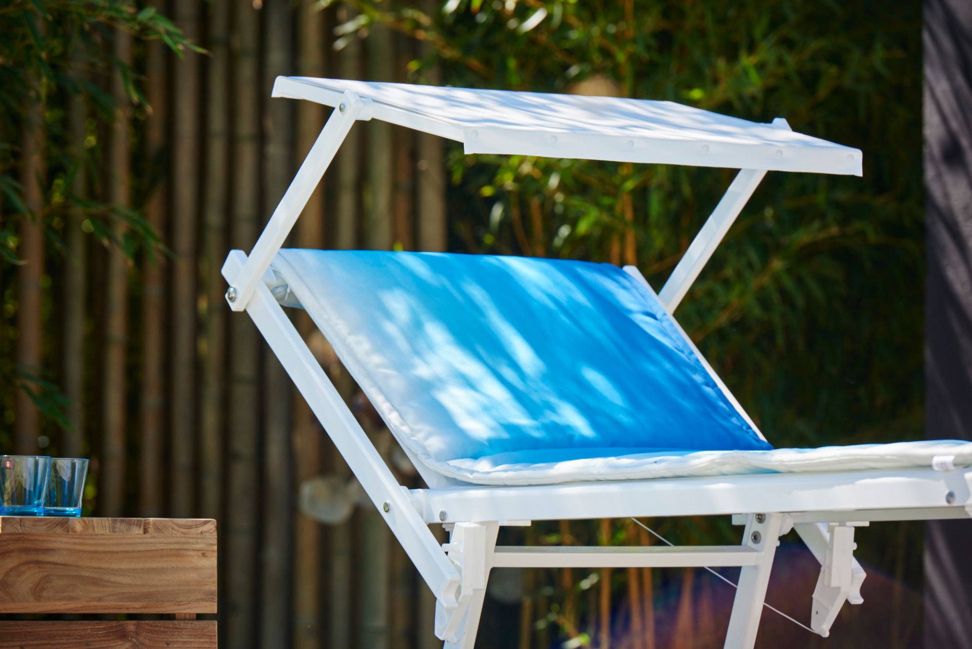 Weiße Sonnenliege mit blauer Padua Aqua Auflage von Jan Kurtz im Garten.