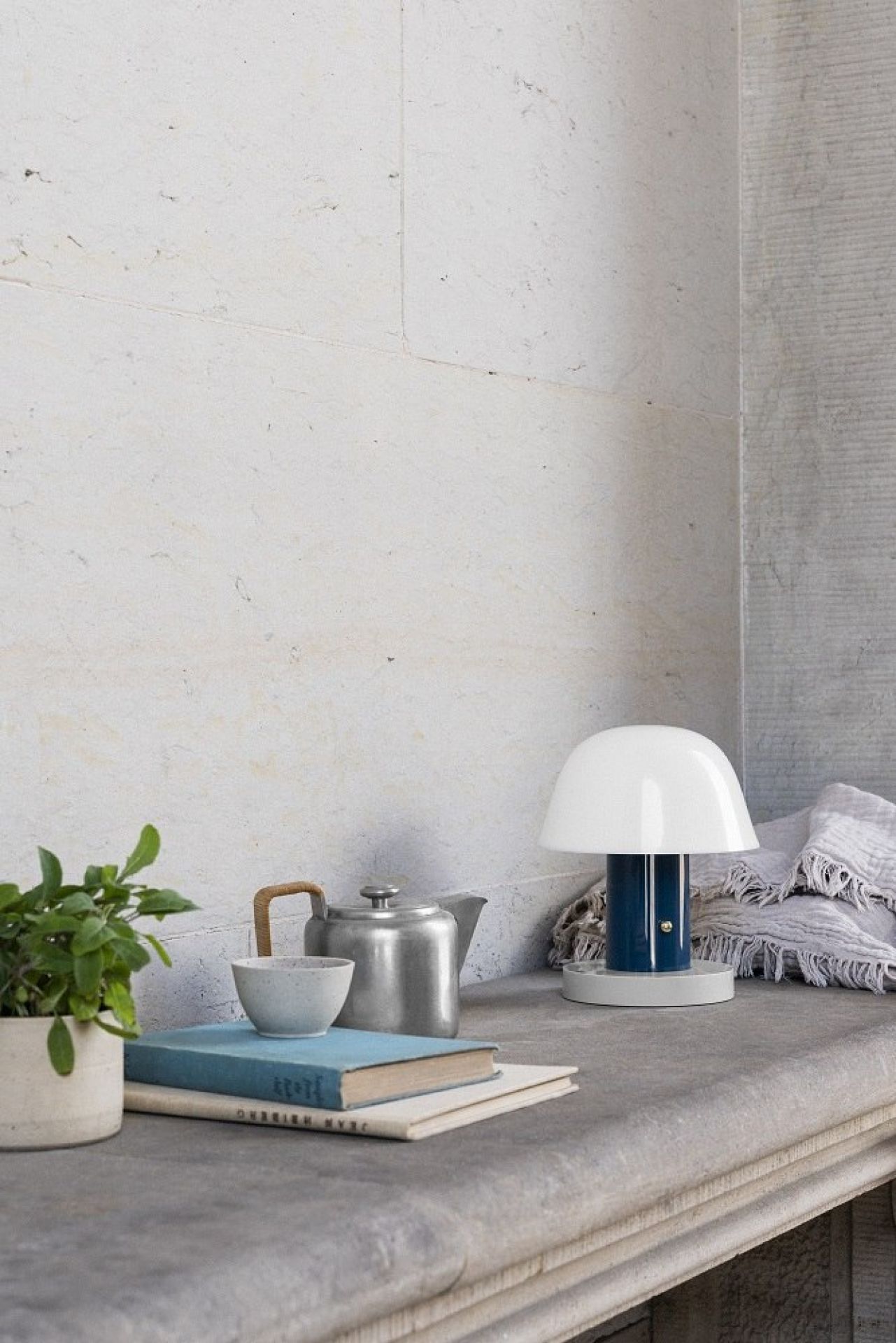 Setago Akkuleuchte Twilight & Sand von AndTradition auf Tisch mit Teekanne und Buch.