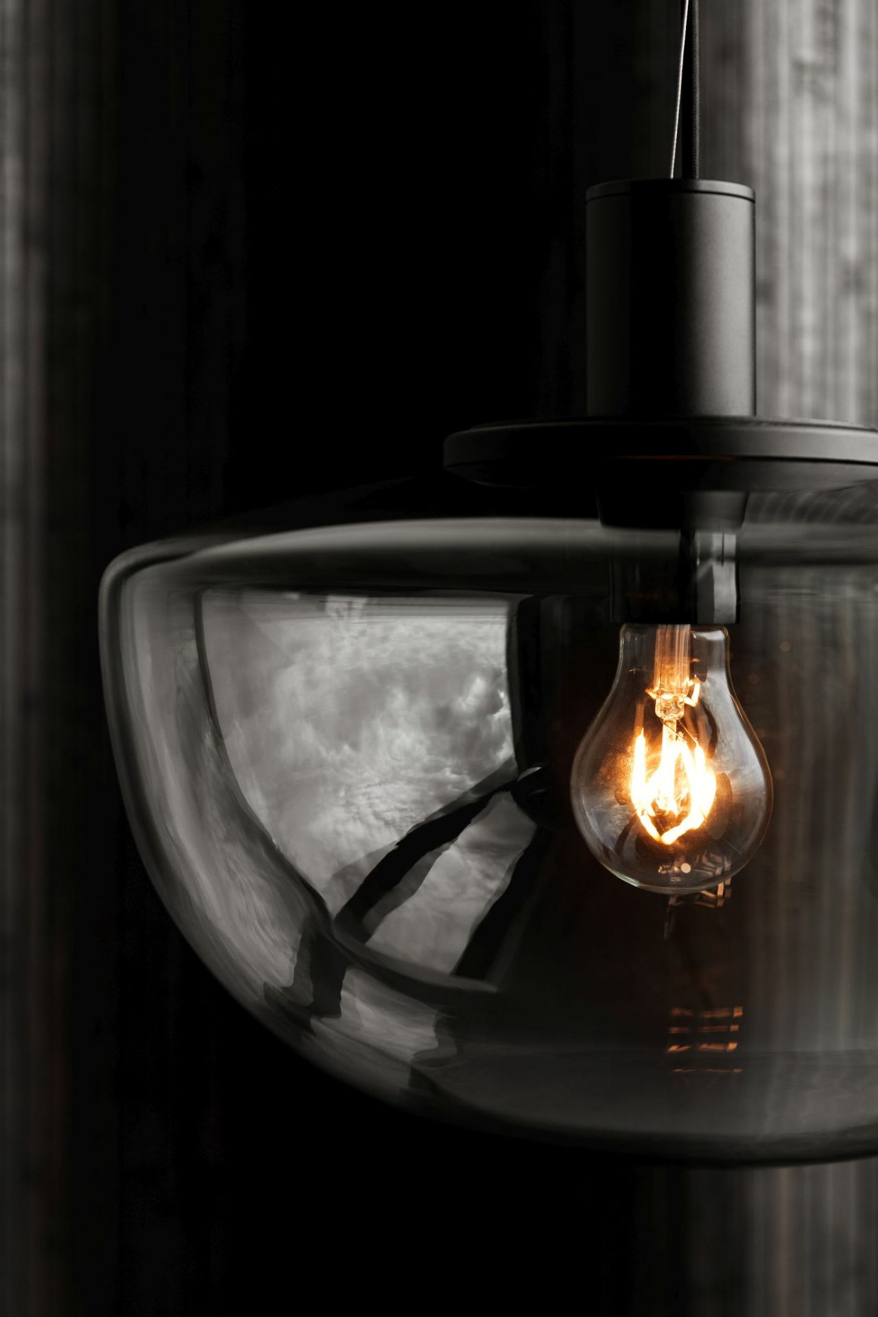 Nahaufnahme der Audo Bank Pendelleuchte mit gläsernem Lampenschirm und warmem Licht.