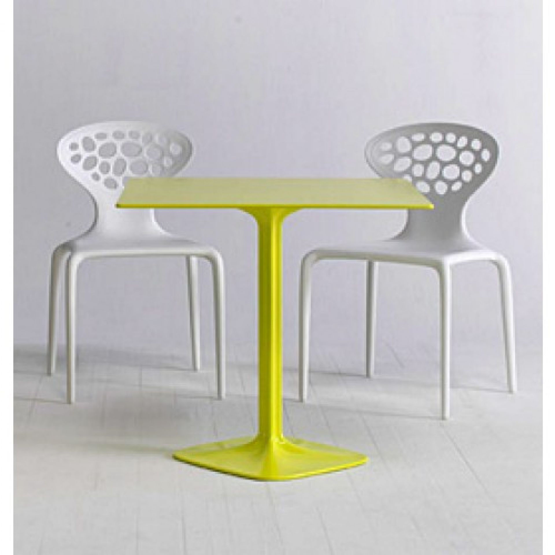 Zwei weiße Supernatural Sedia Stühle mit Löchern und ein gelber Tisch. Modernes Möbeldesign.