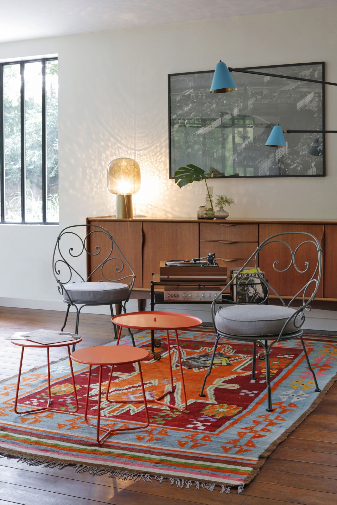 Nahaufnahme von drei kleinen, orangefarbenen Cocotte Beistelltischen von Fermob auf einem bunten Teppich.