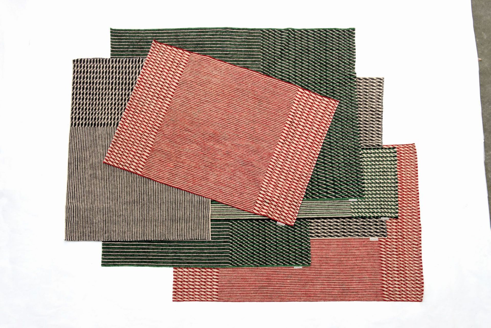 Mehrere farbige Läufer des Nanimarquina Blur Teppichs mit Streifenmuster überlappend auf weißem Hintergrund.