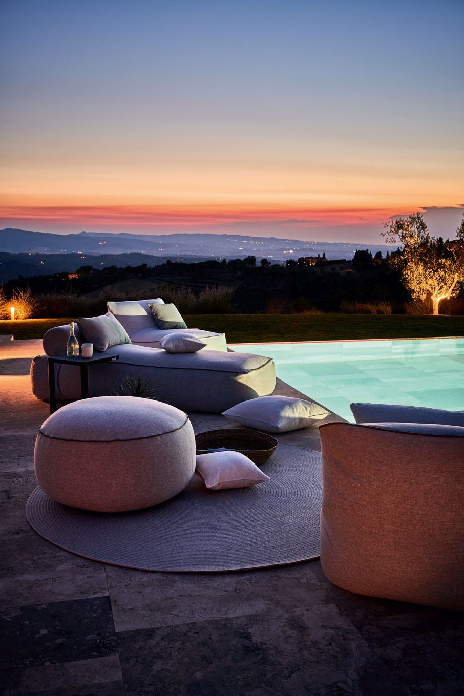 Maliha Lounge Hocker rund von Weishäupl, grauer Outdoor Hocker neben Pool bei Sonnenuntergang.