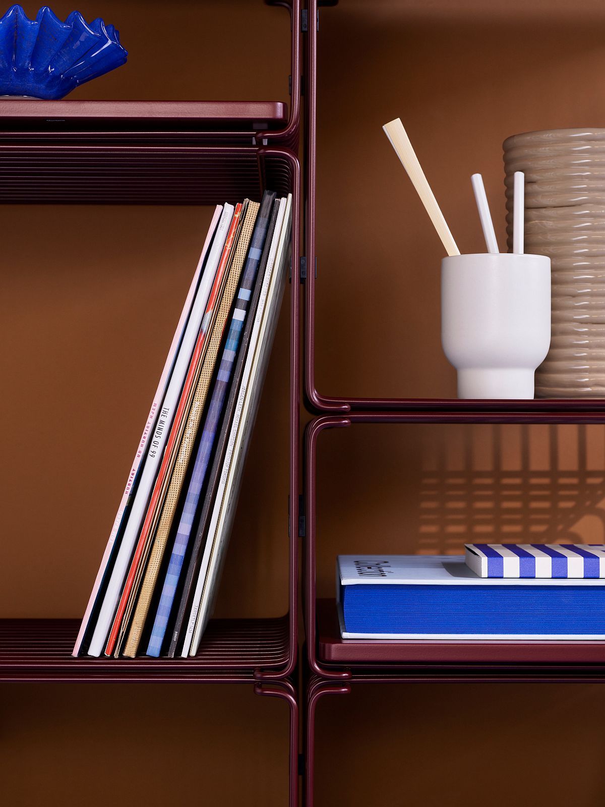 Nahaufnahme eines burgunderroten Panton Wire Cube Regals mit Büchern und Deko-Objekten.