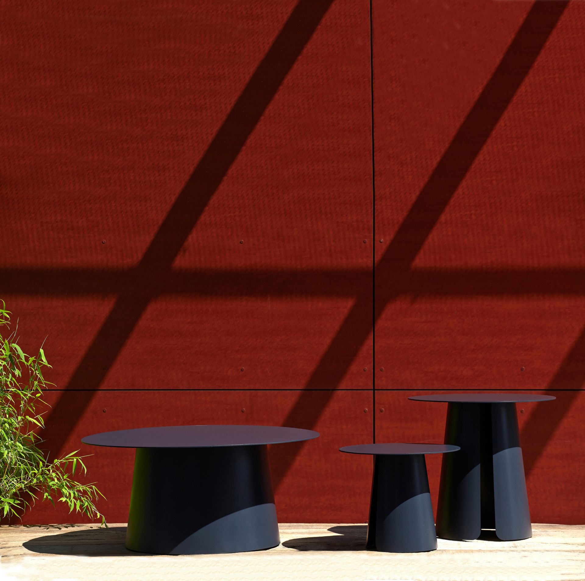 Drei moderne Beistelltische, darunter der Feel Beistelltisch von Jan Kurtz, vor einer roten Wand.