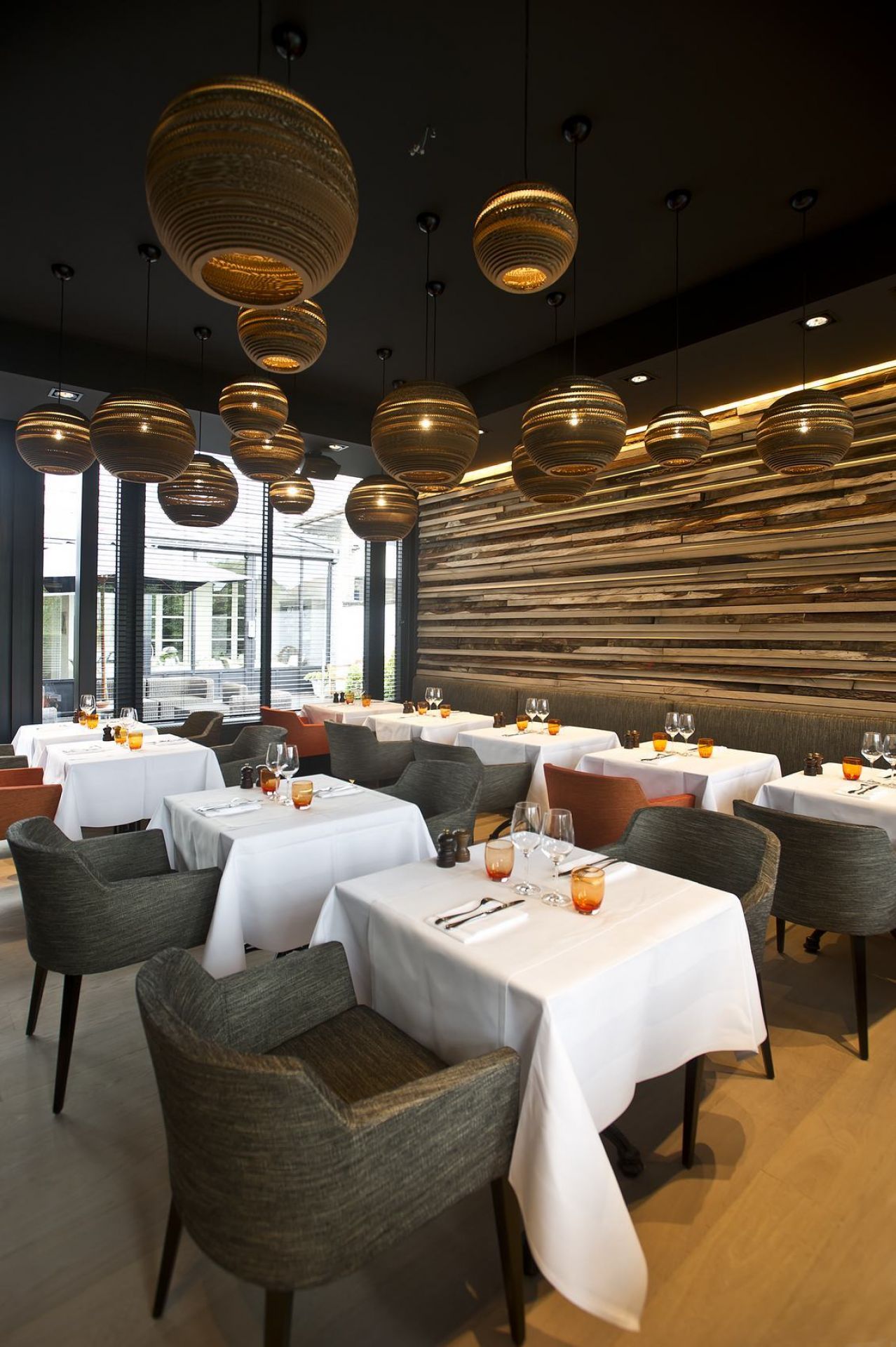 Restaurant mit Tischen und Stühlen unter einer Decke mit vielen hängenden runden Lampen.