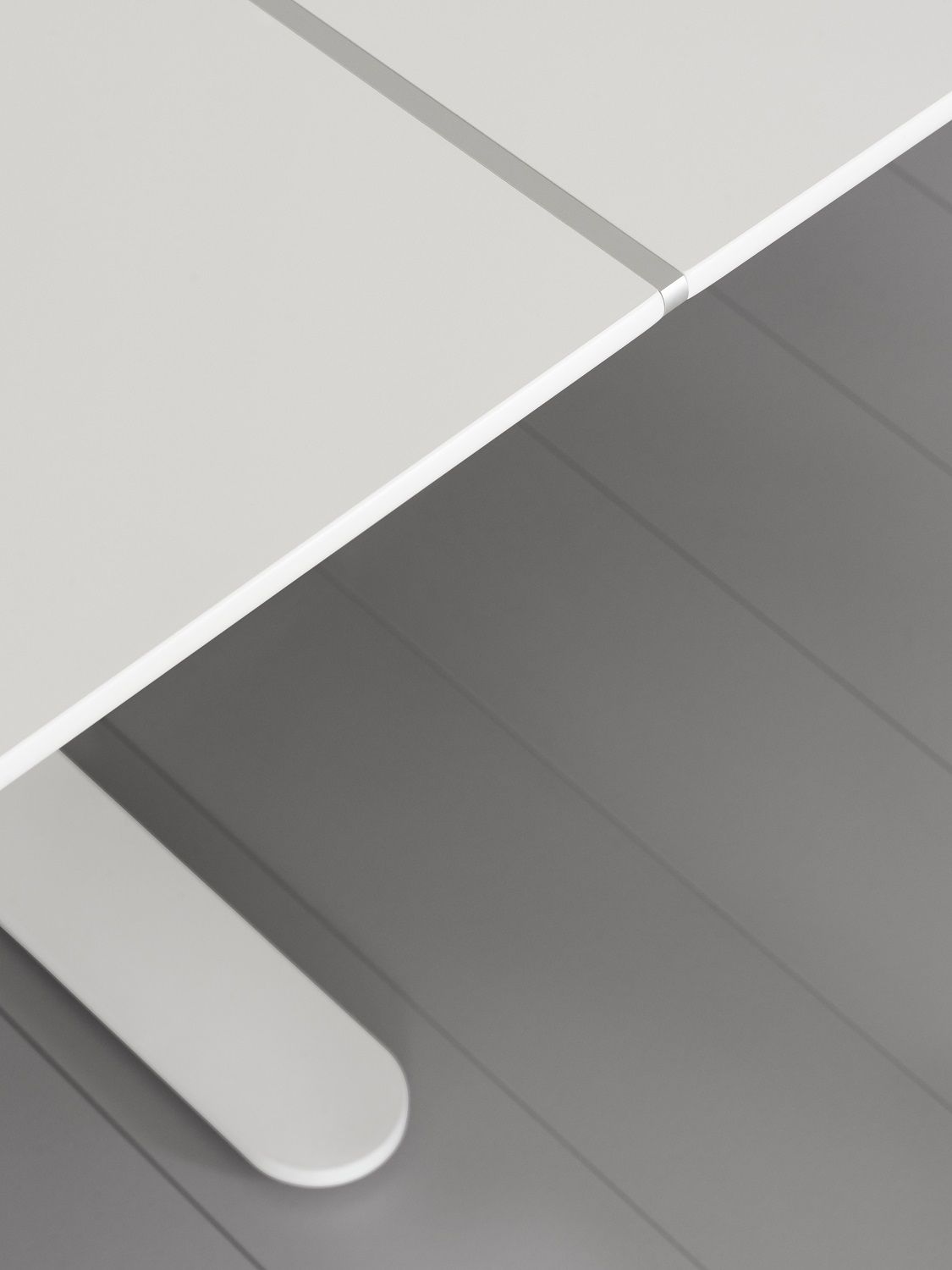 Detailaufnahme: Weißer HiLow Konferenztisch Montana mit Tischbein auf grauem Boden. Büromöbel für Konferenzräume.