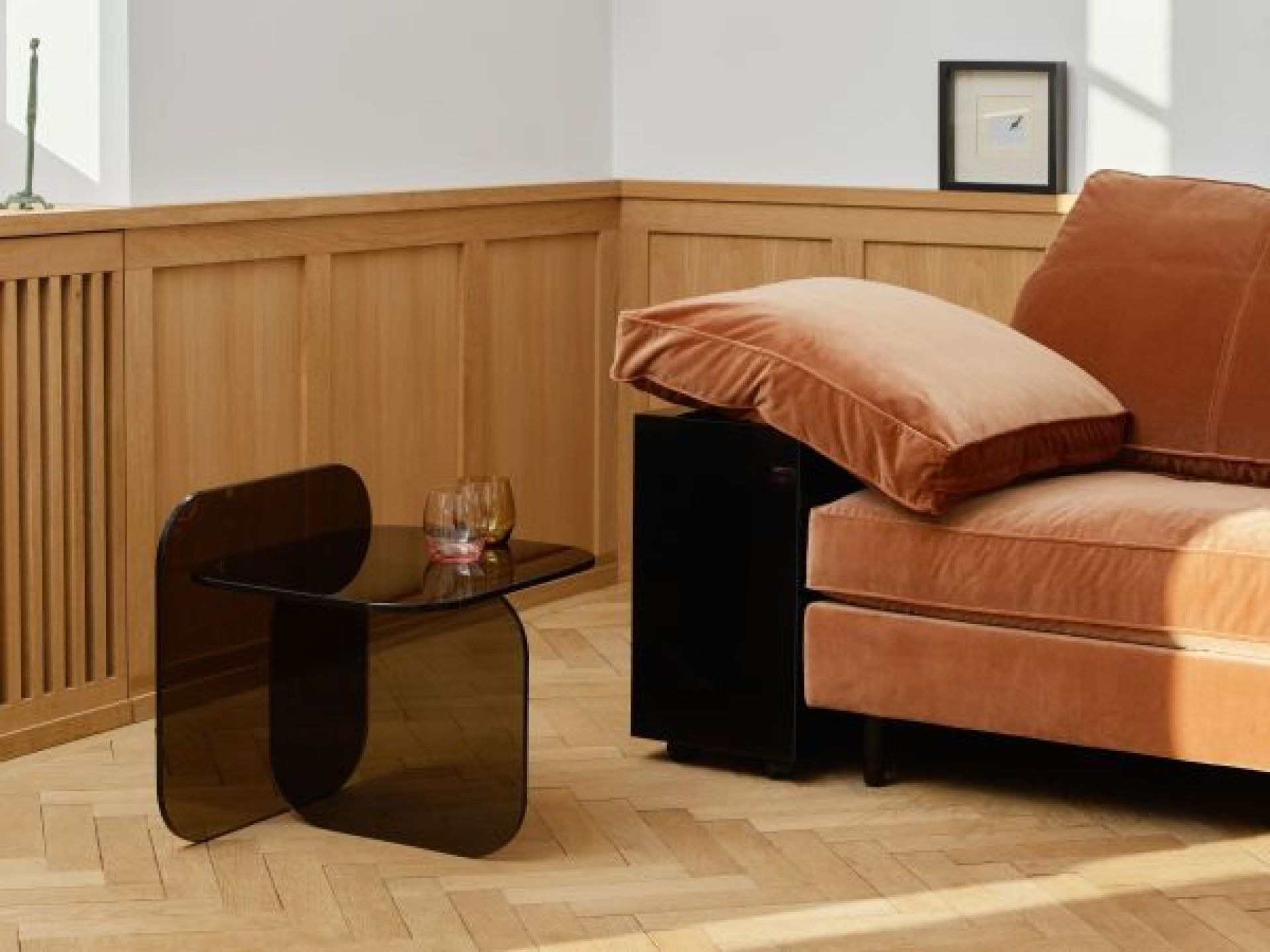 Sol Beistelltisch aus Parsolglas in Bronze von ClassiCon neben einem Sofa im Wohnzimmer.