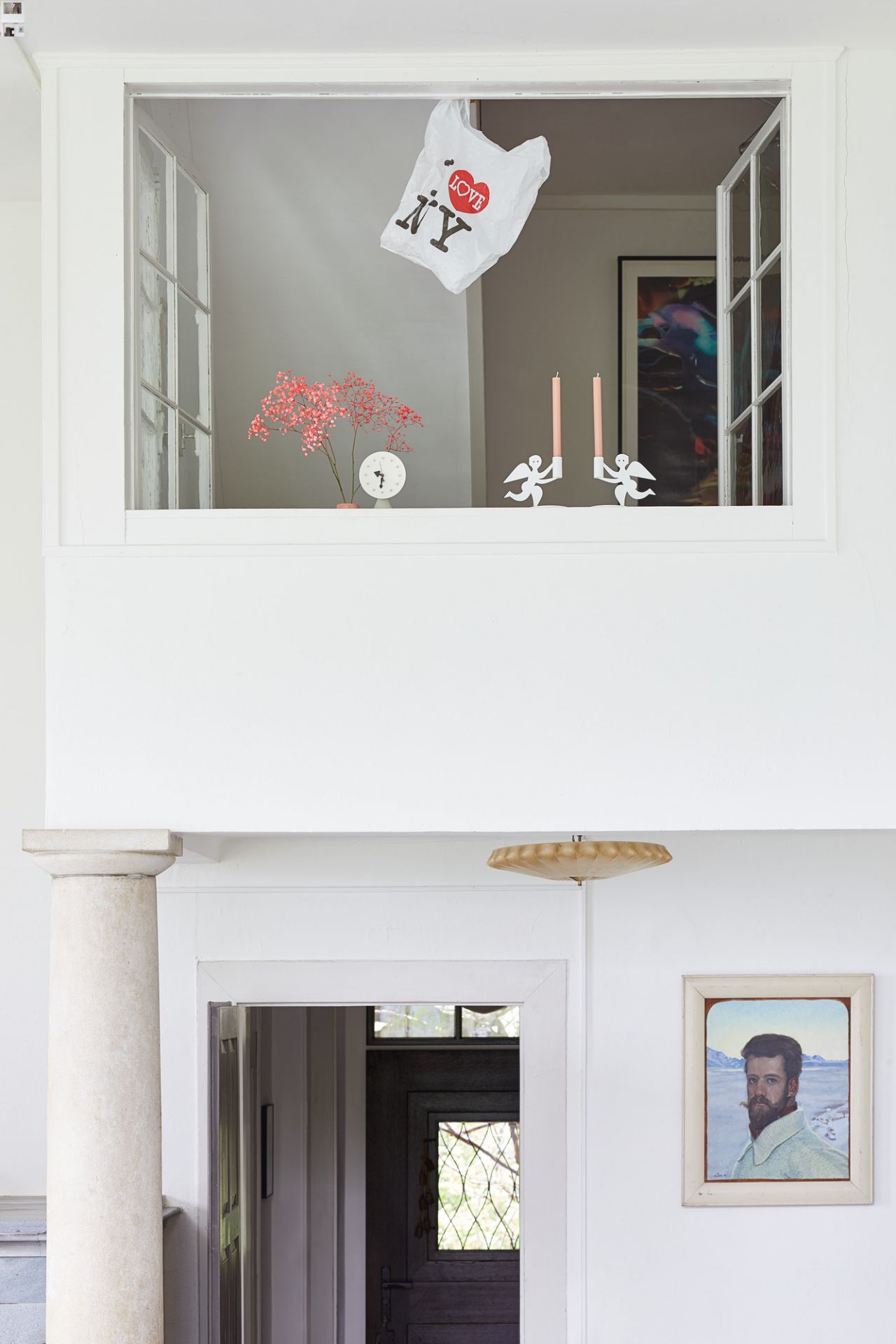 Innenaufnahme mit Vitra Tischuhr auf Fensterbank, neben Blumen, Kerzen und "I Love NY" Tüte.