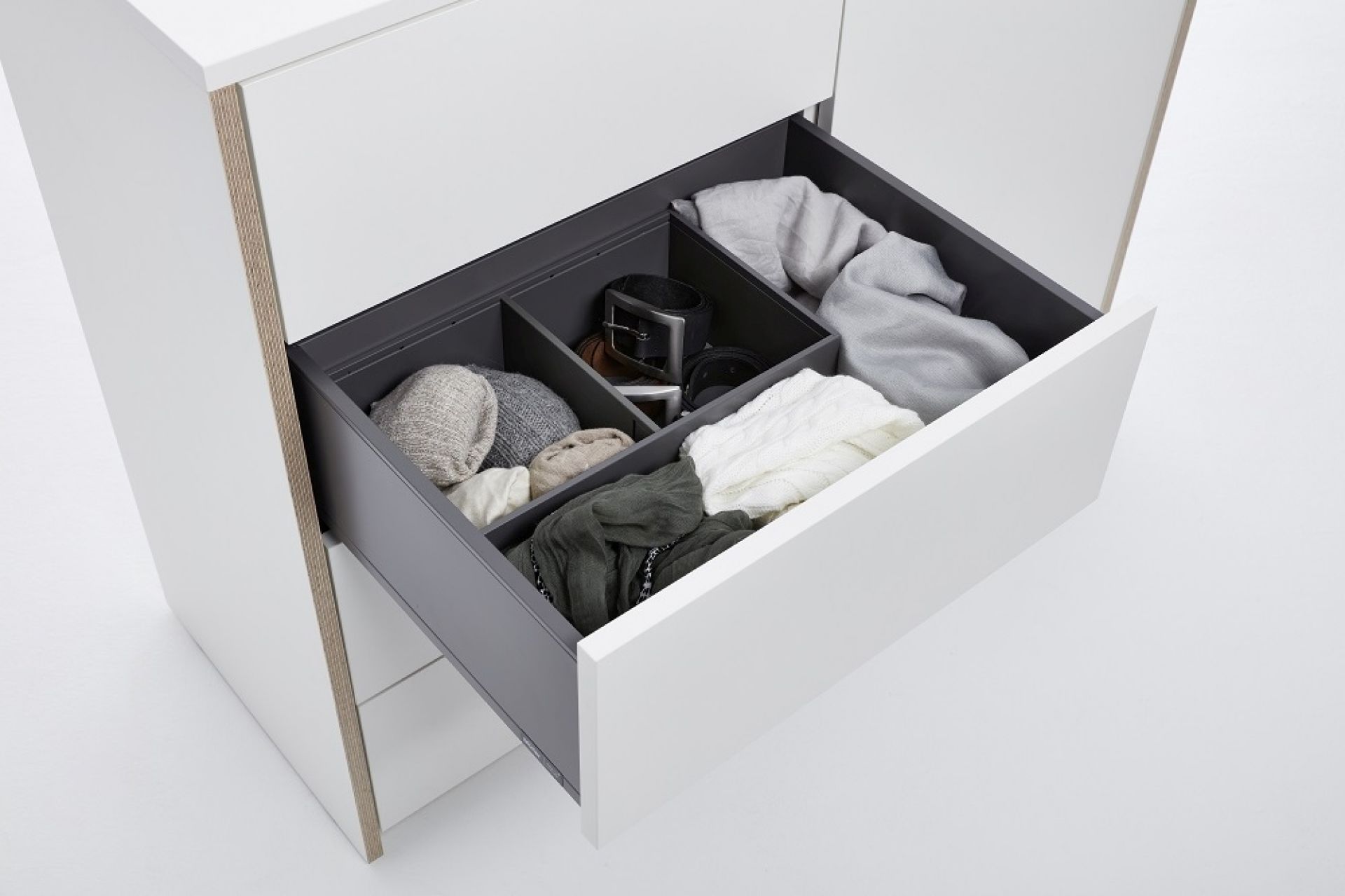 Geöffnete Schublade der Modular Plus Kommode von Müller Möbelwerkstätten mit Fächern und Kleidung.