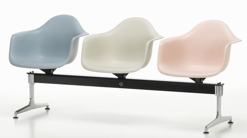 Eames Armchair auf Traverse von Vitra, drei Kunststoffschalen in Pastellfarben auf schwarzem Gestell.