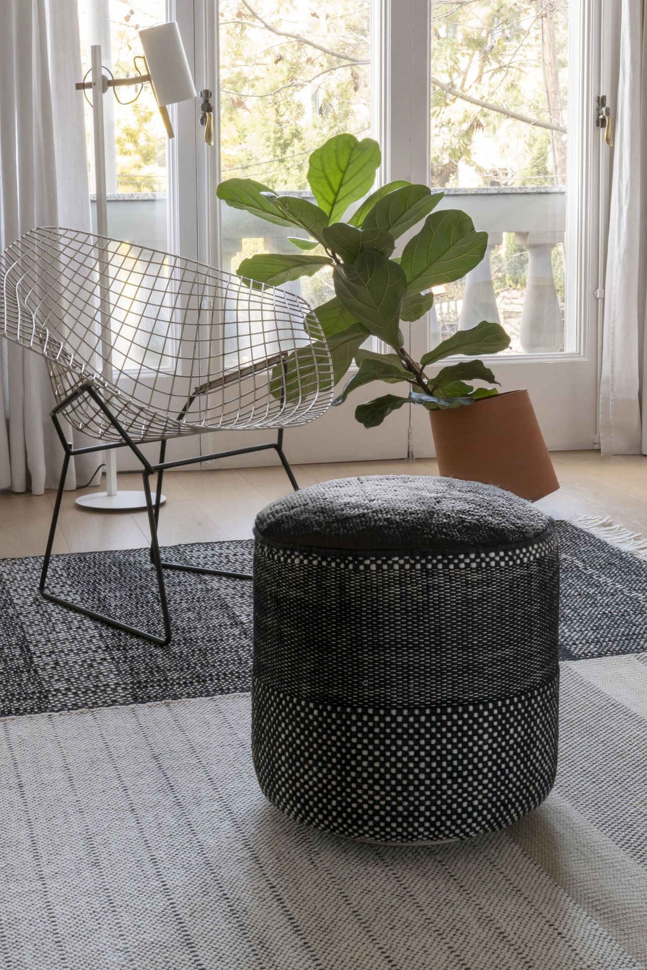 Schwarzer Tres Presian Pouf von Nanimarquina im modernen Wohnzimmer mit Teppich und Stuhl.