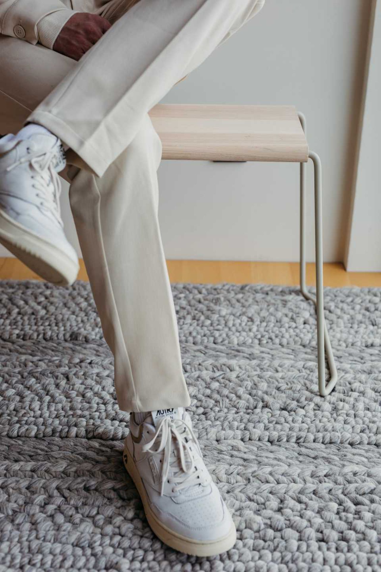 Weiße D:004 Bank von Fuchs & Habicht mit hellem Holz und Person mit weißen Schuhen.