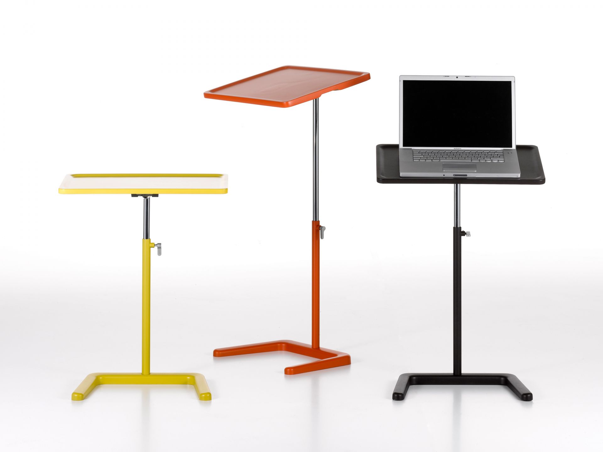 Drei farbige, höhenverstellbare Vitra Beistelltische, davon einer mit Laptop, freigestellt auf Weiß.