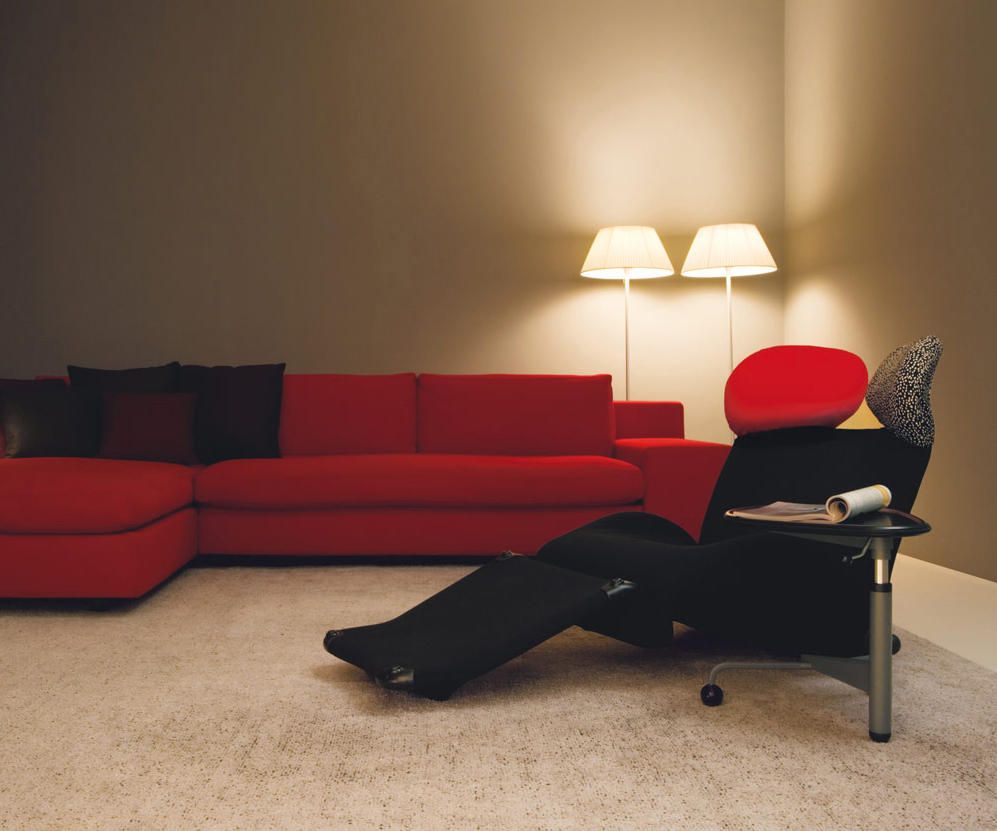 Anthrazitfarbener 111 Wink Sessel von Cassina mit rotem Sofa und Stehlampen im Hintergrund. Designermöbel für Wohnzimmer.