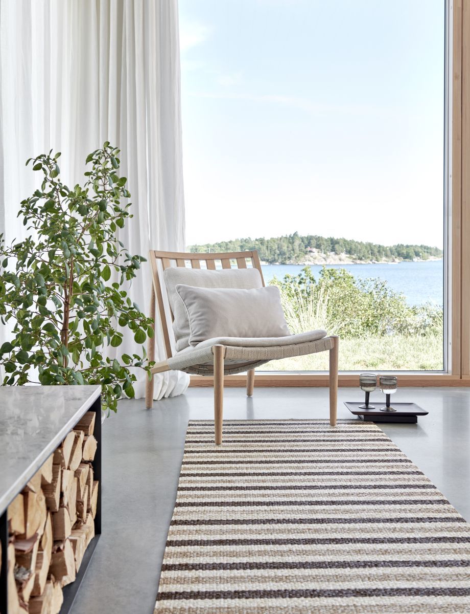 Teo Teppich von Pappelina im Wohnzimmer mit Streifenmuster in Beige und Braun.