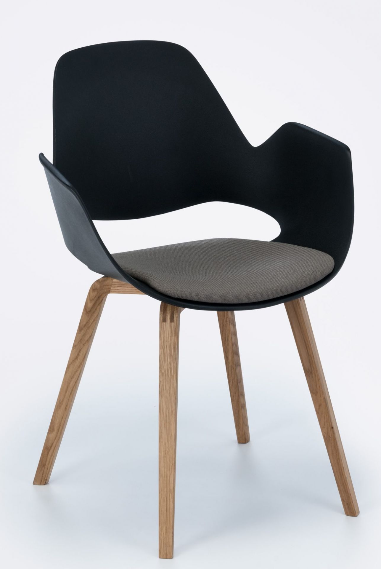Falk Stuhl mit Armlehne von Houe, schwarze Sitzschale, graues Kissen und Eichenholzbeine.