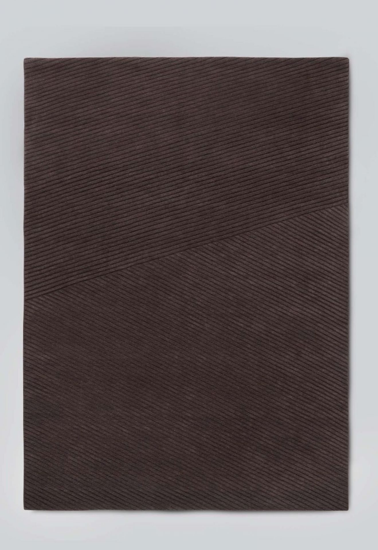 Nahaufnahme des dunkelbraunen Row Teppichs von Northern mit feiner Rippenstruktur.