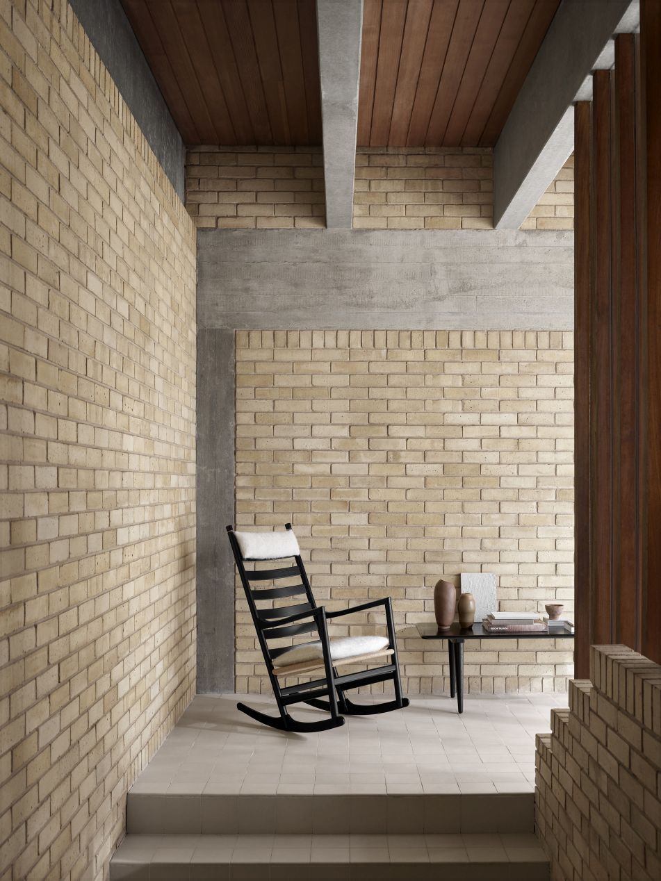 CH45 Schaukelstuhl von Carl Hansen & Søn aus schwarzer Eiche mit Polsterung vor Backsteinwand.