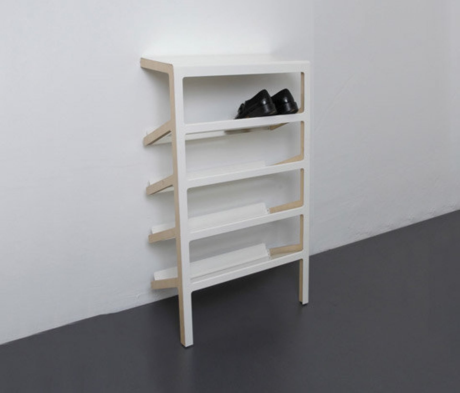 Weißes Mila Schuhregal mit vier Ablagen, an einer Ecke stehend. Schuhe auf der obersten Ablage.