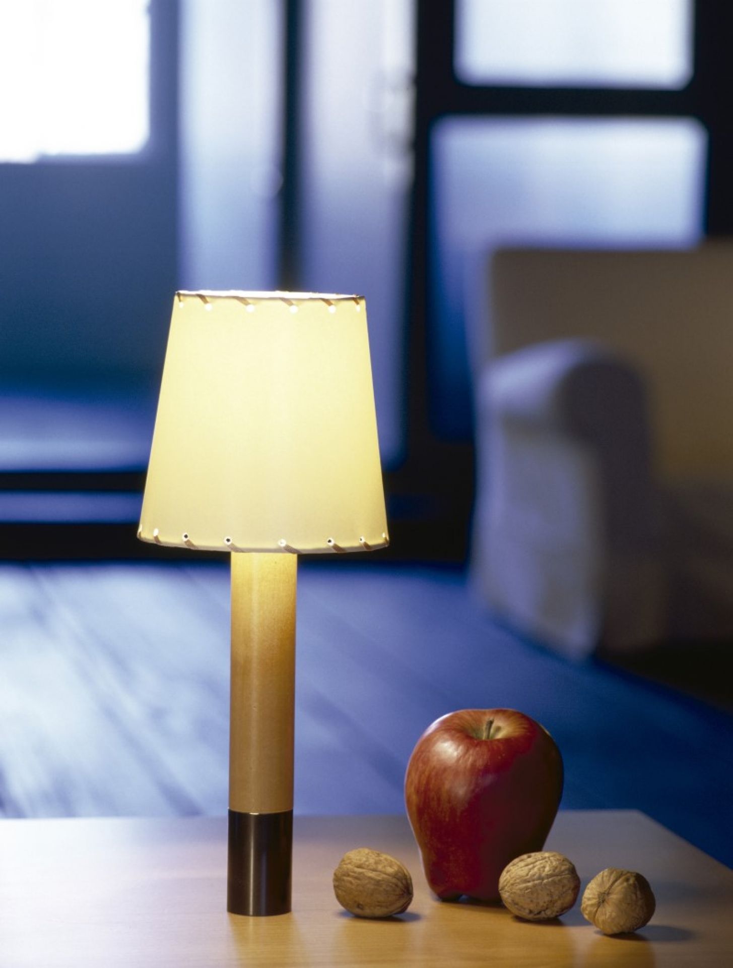 Basica Minima Tischleuchte von Santa & Cole mit Lampenschirm, Apfel und Nüssen auf Tisch.