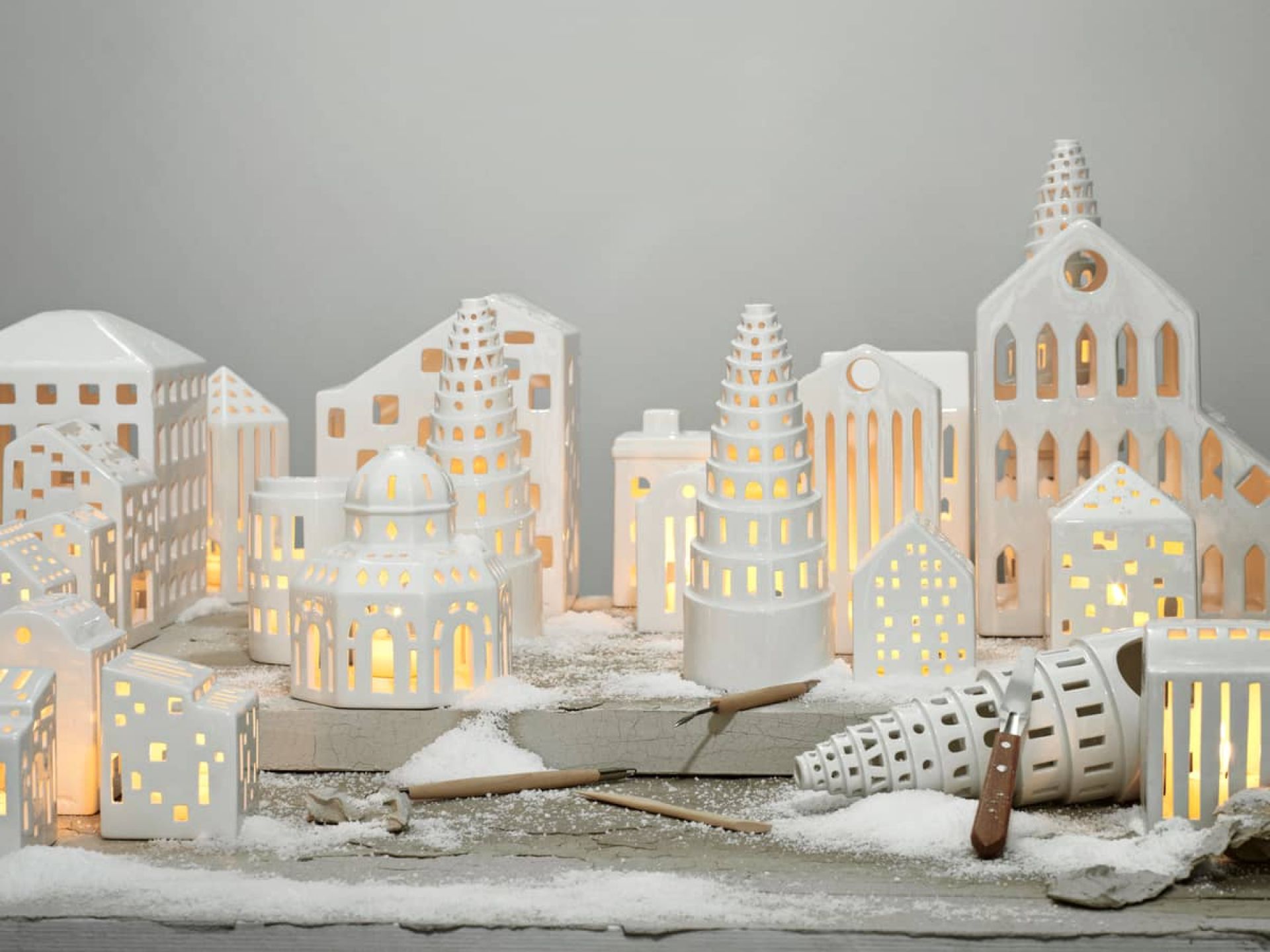 Detailaufnahme von Kähler Urbania Lichthäusern, die eine kleine Stadt aus weißer Keramik mit warmem Kerzenlicht bilden.