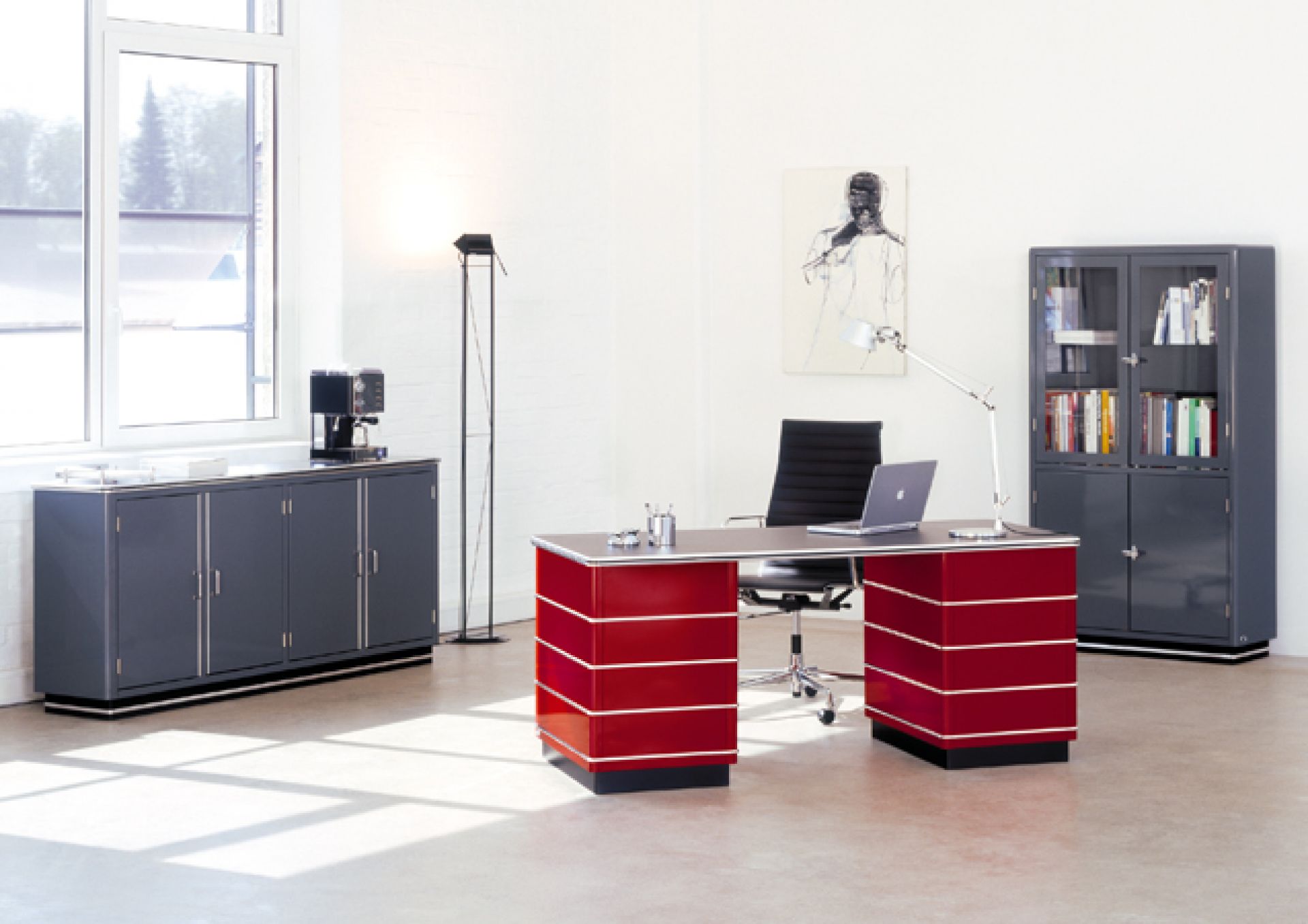 TB229 Classic Line Schreibtisch von Müller Möbelfabrikation in Rot, mit Büromöbeln und Accessoires in einem hellen Raum.
