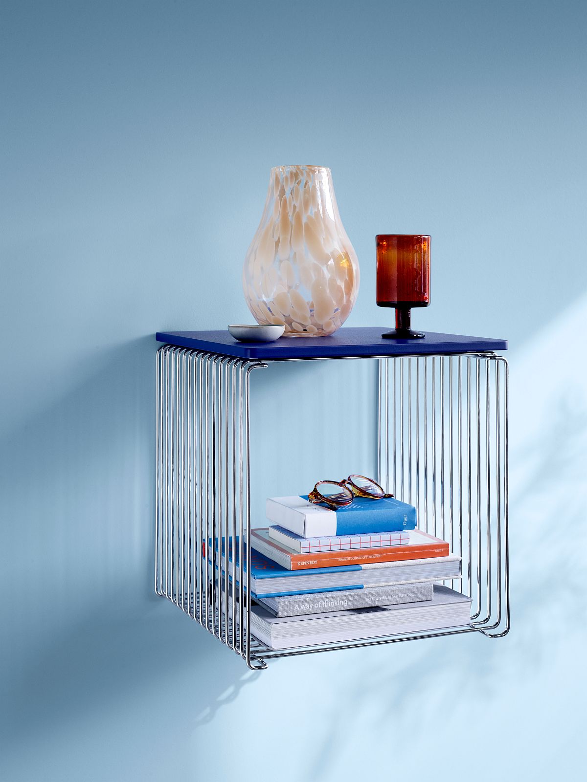 Nahaufnahme des Panton Wire Regals mit blauer Montana Abdeckplatte (B 35 cm) und Dekoration.