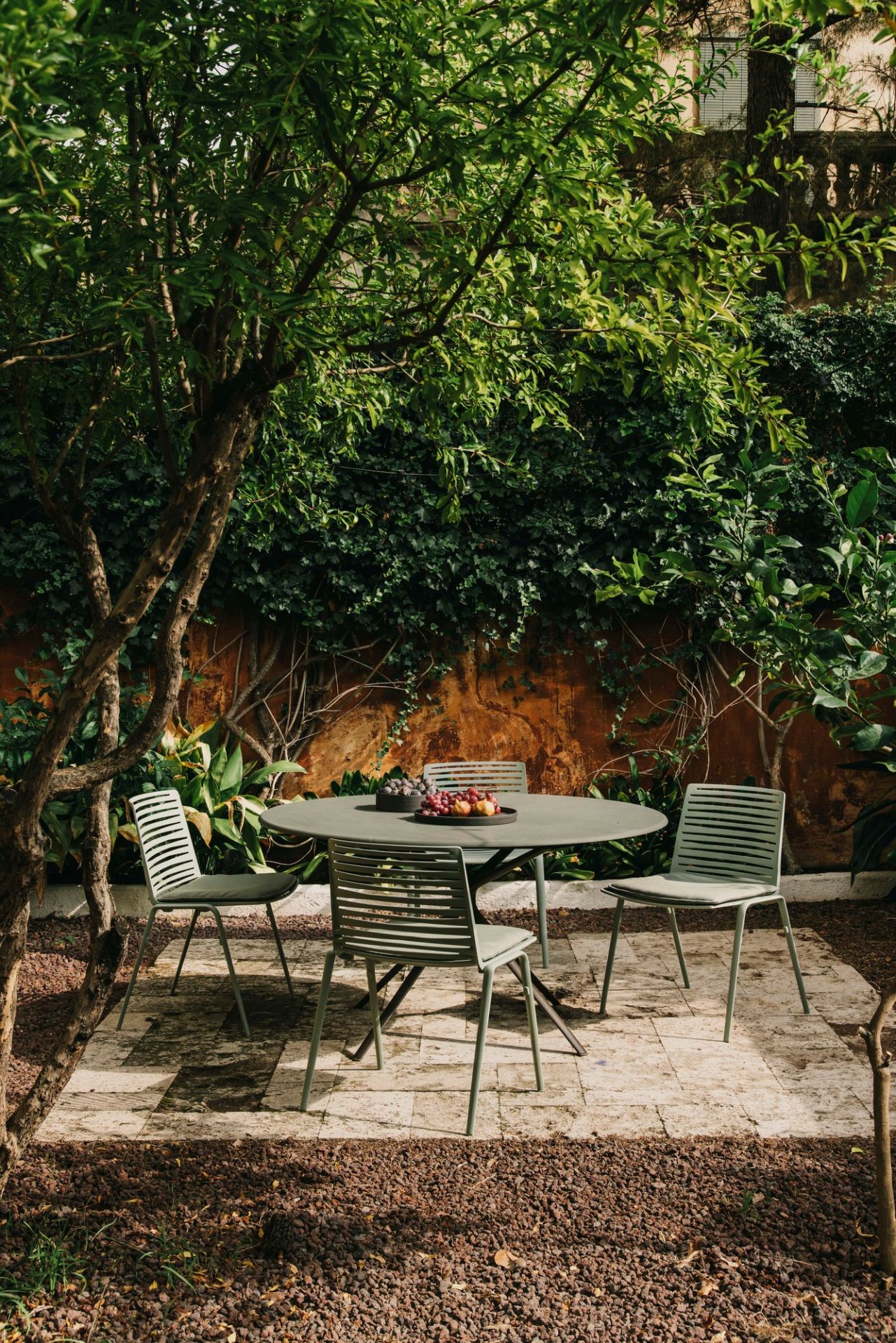 Zebra Outdoor Stühle Fast mit rundem Gartentisch auf einer Terrasse, umgeben von üppigem Grün.