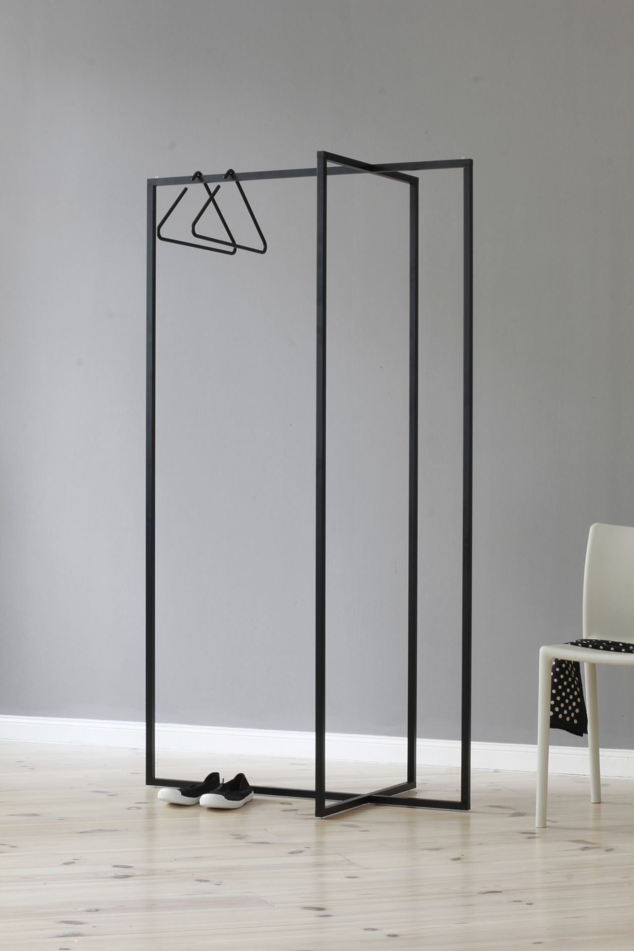 Roomsafari Modular Frames L Garderobe: Schwarzer, minimalistischer Kleiderständer mit Kleidung und Schuhen im Raum.