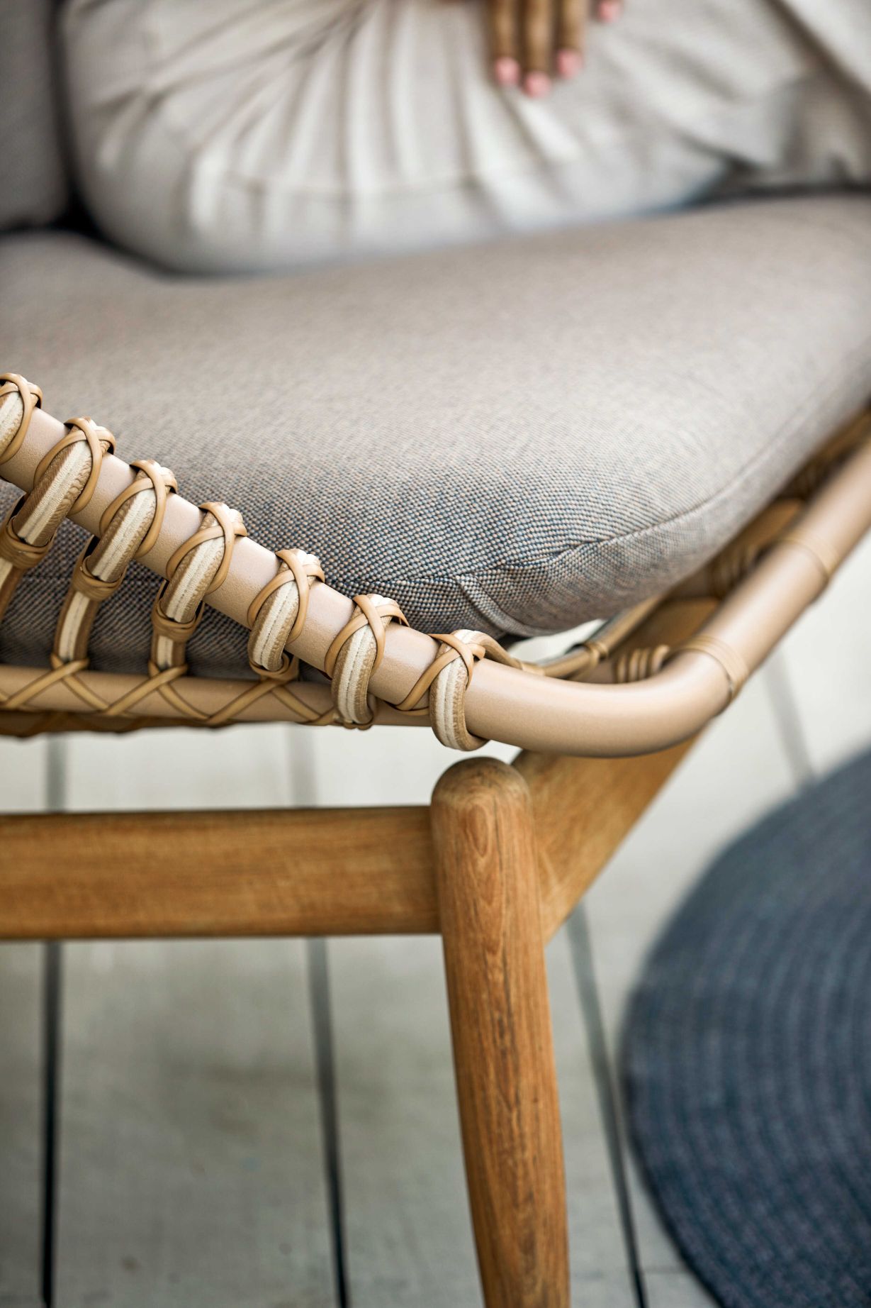 Detailaufnahme des Cane-Line Strington Outdoor Sofas: Naturfarbenes Rattan, bequemes Sitzkissen und Holzgestell. Gartenmöbel für stilvolles Wohnen.