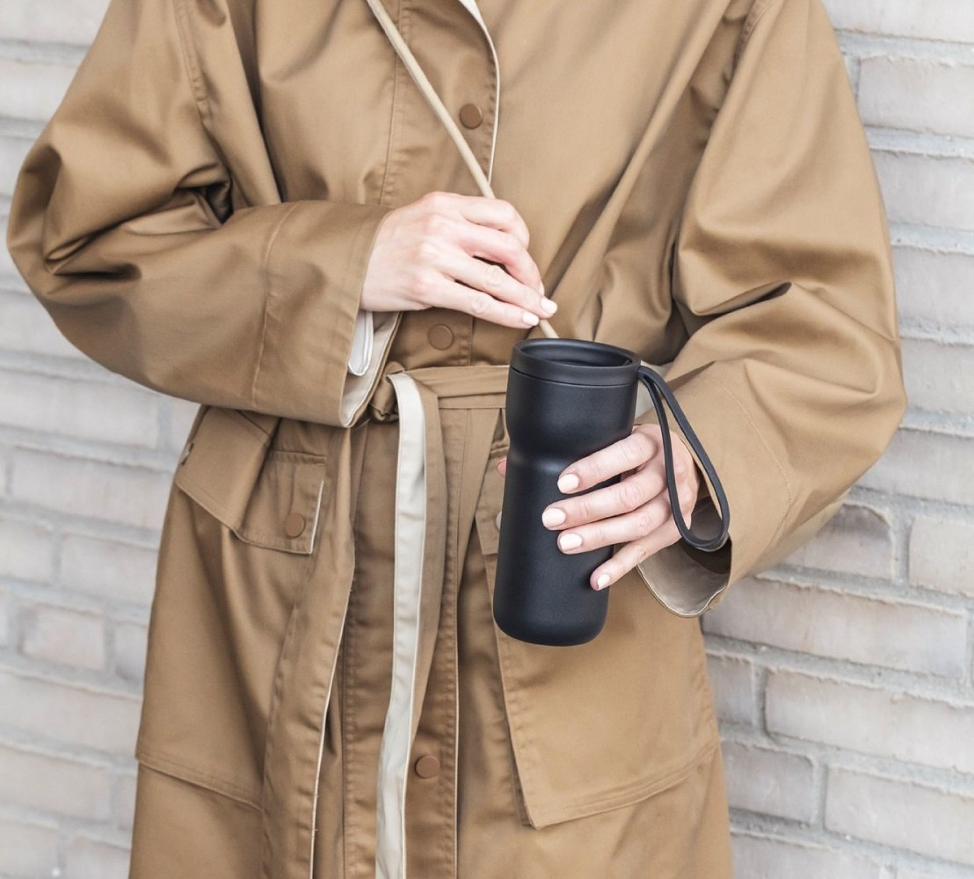 Frau hält schwarzen Eva Solo Nordic Kitchen Thermobecher. Isolierbecher für Kaffee und Tee.