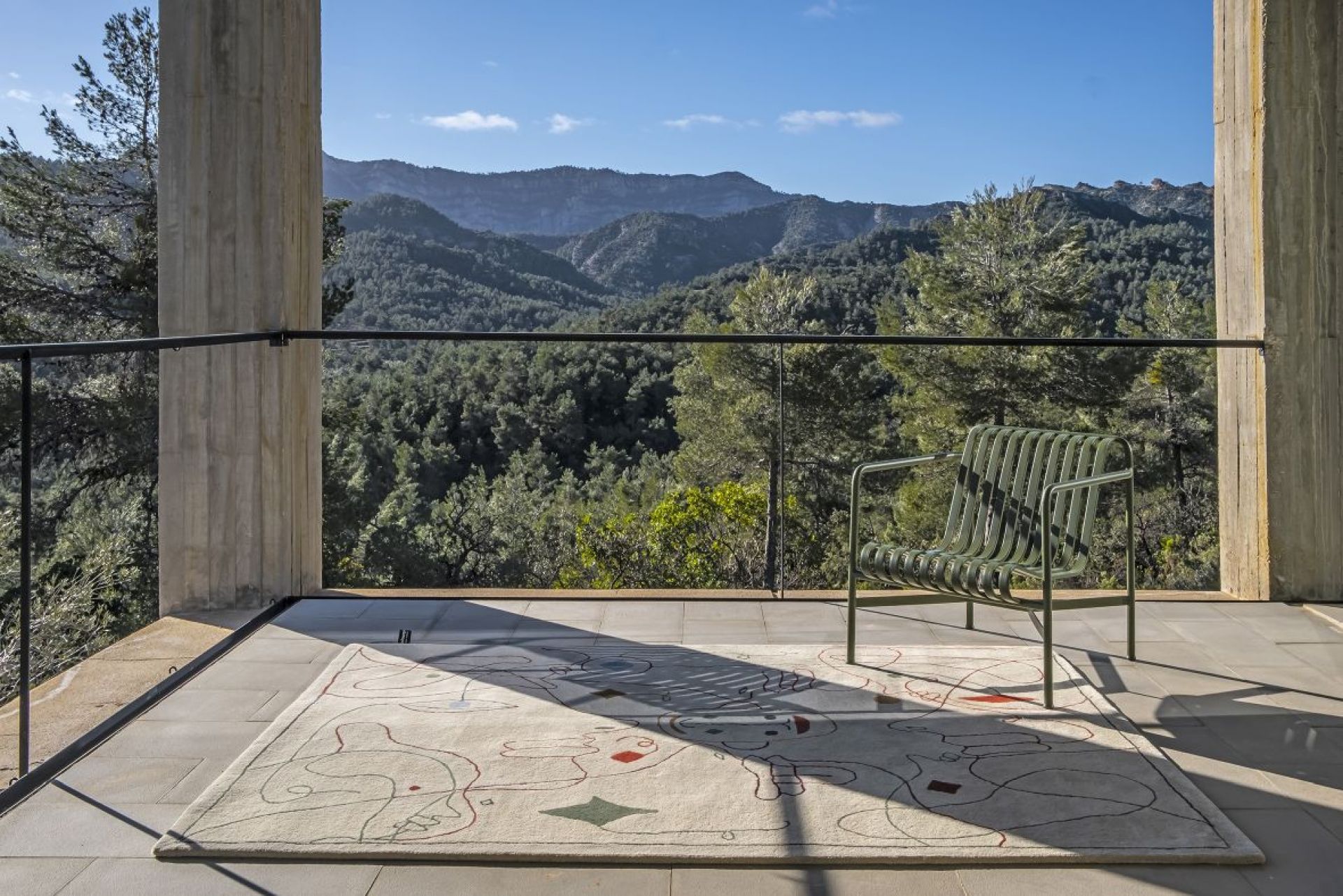 Nanimarquina Teppich Silhouette Outdoor auf Terrasse mit Stuhl und Bergblick. Design Teppich für Außen.