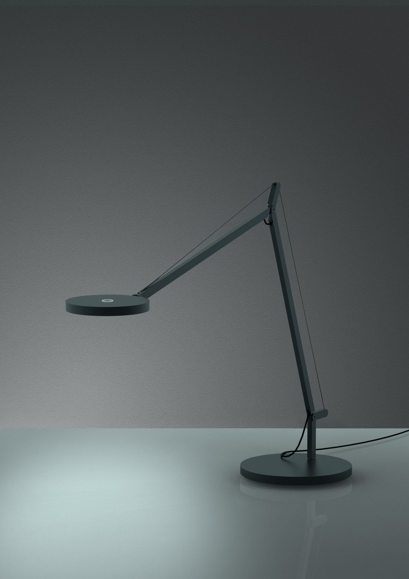 Dunkelgraue Demetra Tischleuchte von Artemide mit verstellbarem Arm und rundem Leuchtenkopf.