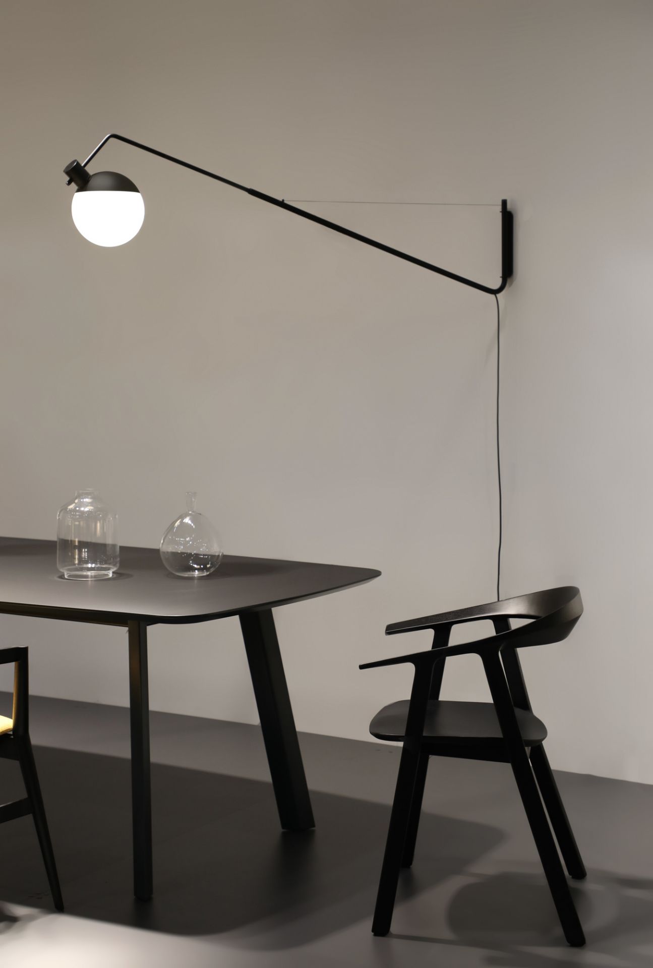 Schwarze Baluna Wandleuchte von Grupa über Esstisch mit Stuhl. Moderne Innenbeleuchtung für Wohnzimmer.