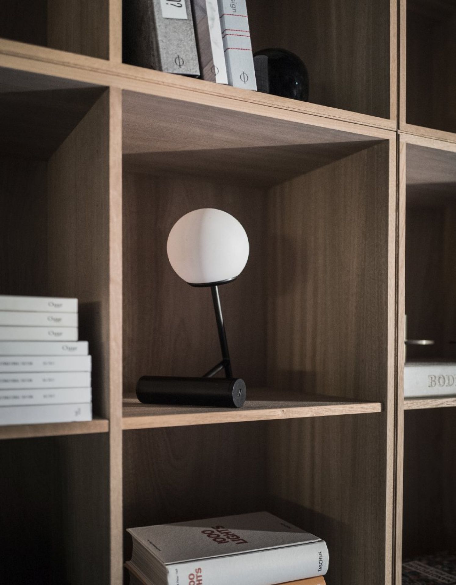 Nahaufnahme der schwarzen Audo Phare LED Tischleuchte mit weißem Lampenschirm im Regal.