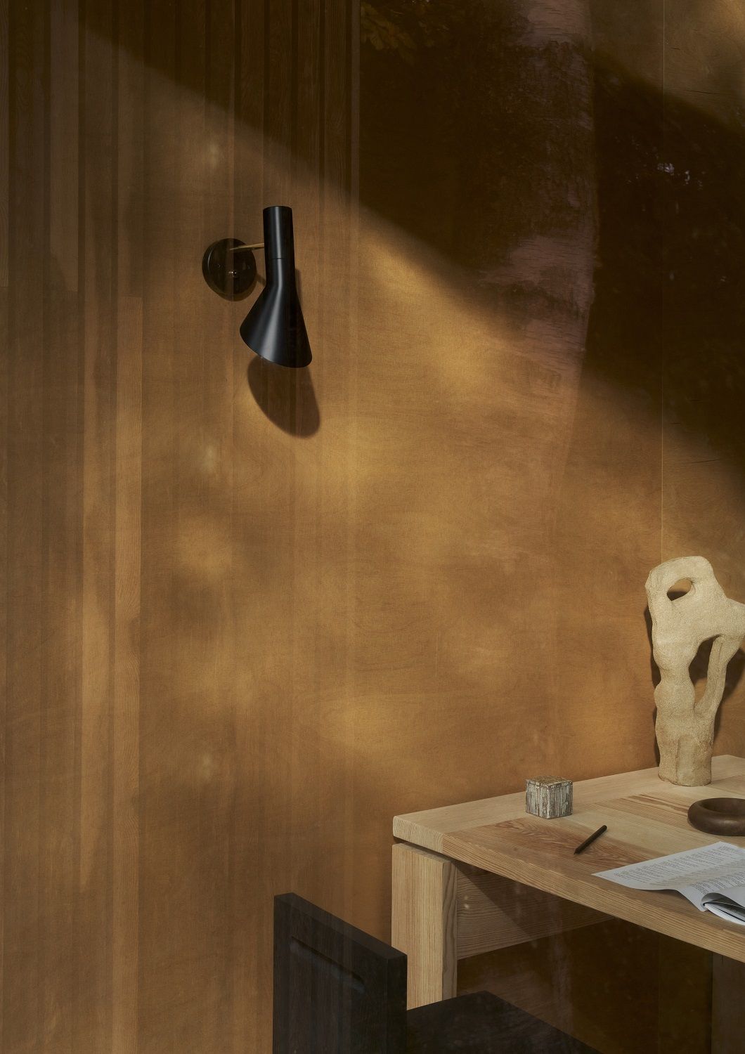 Schwarze AJ Wandleuchte von Louis Poulsen an einer Wand, minimalistisches Design für Wohnraumbeleuchtung.