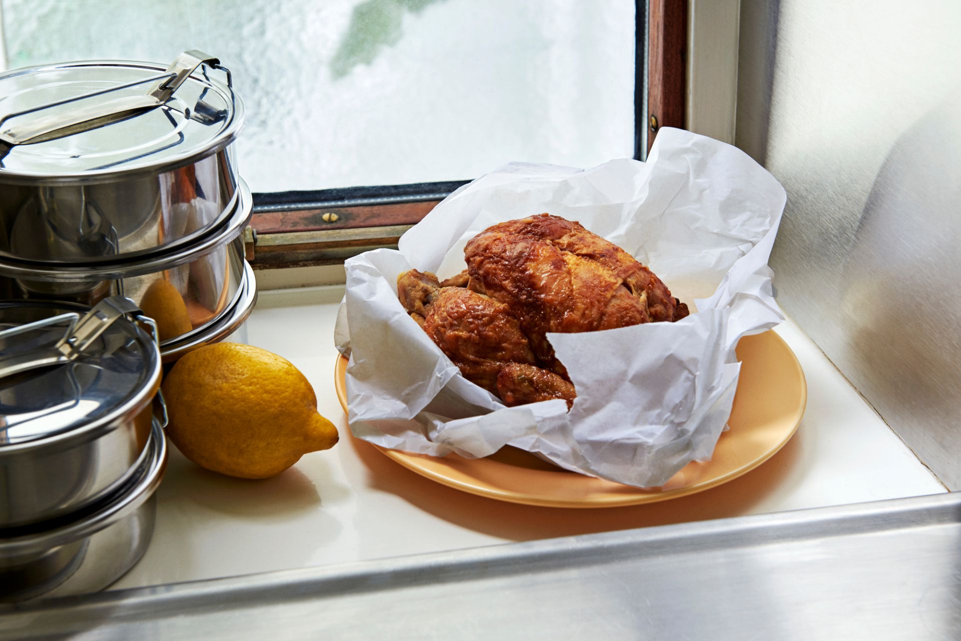 Stapelbare runde Steel Lunch Box Brotdosen aus Edelstahl neben Zitrone und Brathähnchen.