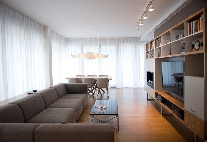 Wohnzimmer mit grauem Match Sofa von Prostoria, Esstisch und modernem TV-Möbel.